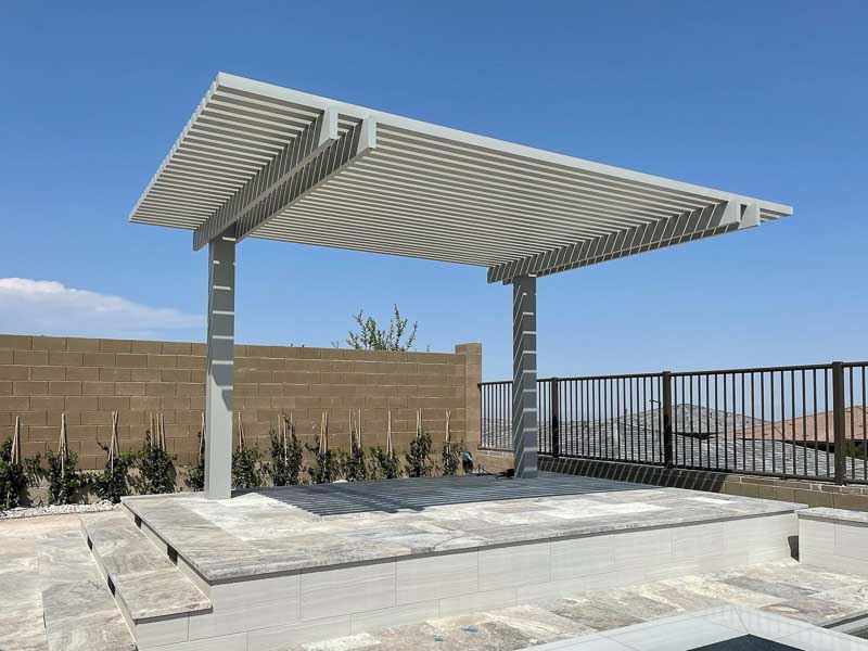 White 4K Aluminum cantilever pergola with a louvered roof over a stone patio with a hillside view